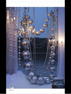 a bunch of balls and chains hanging from the ceiling in front of a window with sheer curtains