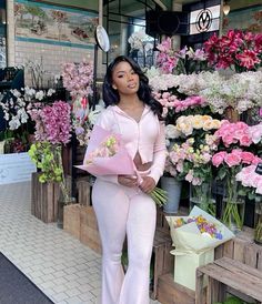 a woman standing in front of flowers at a flower shop with pink and white bouquets