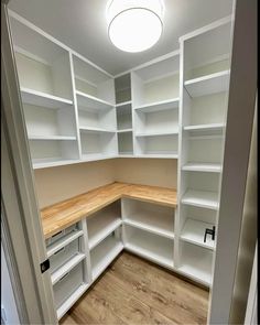 an empty pantry with white shelves and wood counter tops in the middle of it's room