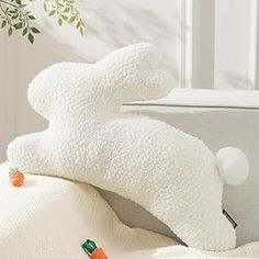 a white stuffed animal sitting on top of a bed next to a pillow and blanket