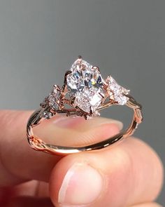 a person holding a ring with three stones on it's sides and two diamonds in the middle