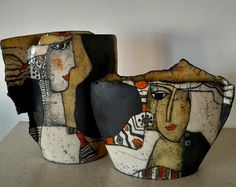 two vases sitting on top of a table next to each other with faces painted on them