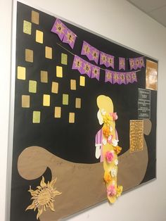 a bulletin board with flowers on it in an office cubicle decorated with purple and yellow decorations