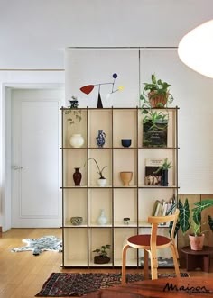 a living room filled with furniture and lots of plants on top of bookshelves