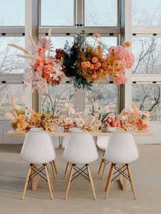 the table is set with white chairs and flowers