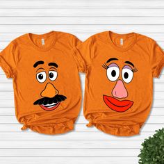 two orange shirts with faces on them, one is wearing a mustache and the other has a