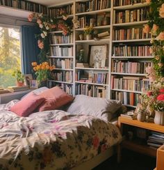 a bed sitting in front of a book shelf filled with books next to a window