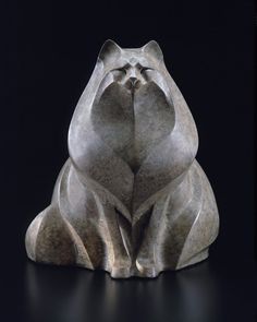 a cat statue sitting on top of a black surface with its eyes closed and it's head turned to the side