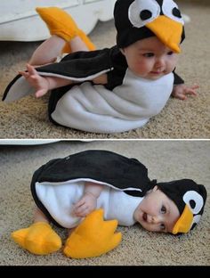 a baby in a penguin costume laying on the floor