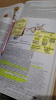 an open book with sticky notes attached to it and a pen resting on the page