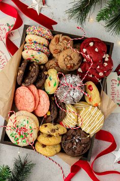 a box filled with lots of different types of cookies and pastries next to a christmas tree