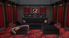 an empty theater room with black couches and red carpet