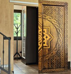 an intricately designed wooden door is open to reveal the entrance into a room with tile flooring and walls