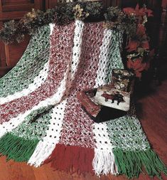 a crocheted blanket is on the floor next to a suitcase and christmas tree