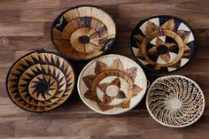 four baskets sitting on top of a wooden floor next to each other with designs in them