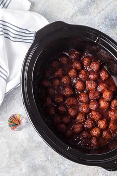 a crock pot filled with meatballs sitting on top of a table next to a napkin