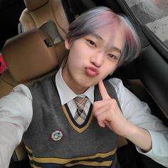 a young man in a school uniform making a funny face while sitting in a car