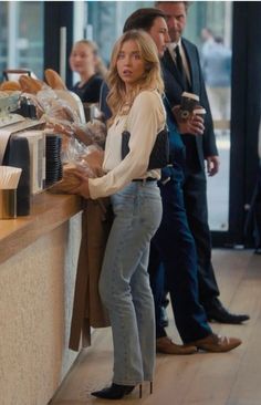 a woman is standing at the counter in front of some people and looking over her shoulder