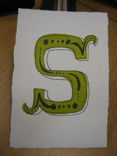 the letter e is made up of green and black letters on white paper with dots