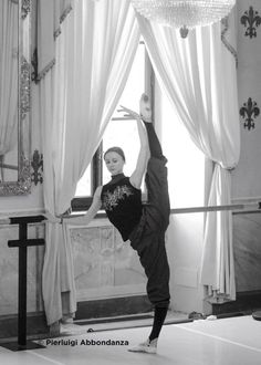 a woman is doing a handstand in front of a window with white curtains