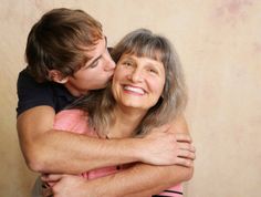 an older couple hugging each other in front of a wall with the caption's name on it