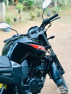 a black motorcycle parked on top of a dirt road