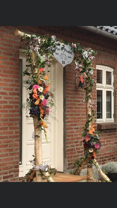 an outdoor wedding arch with flowers and greenery on the side of a brick building