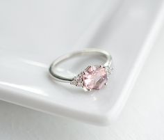 a pink diamond ring sitting on top of a white plate