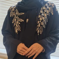 Introducing our Gold Floral Embroidered Open Abaya -- a pinnacle of luxury and refinement. Adorned with intricate floral embroidery, this timeless masterpiece features versatile pop-up buttons for effortless styling. Crafted from 100% Nida, it ensures comfort and durability, while the set includes a matching hijab and a complementary belt for a coordinated, polished look. Elevate your wardrobe with this symbol of opulence, machine washable for your convenience. Immerse yourself in authentic craftsmanship, proudly Made in the UAE. 2 Piece Abaya Set, includes Embroidered Butterfly Abaya Embroidered Chiffon Hijab Traditional Embroidered Long Sleeve Khimar, Traditional Long Sleeve Embroidered Khimar, Traditional Niqab For Eid, Black Embroidered Abaya For Wedding, Black Embroidered Wedding Abaya, Wedding Black Embroidered Abaya, Black Open Abaya, Embroidered Hijab, Butterfly Abaya