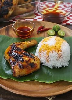 a plate with chicken, rice and sauces on it next to other food items