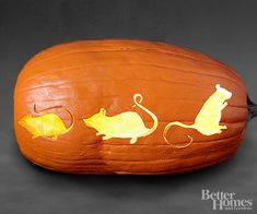 a carved pumpkin with two mice and a mouse on it's side, sitting in front of a black background