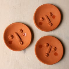 three clay plates with faces drawn on them