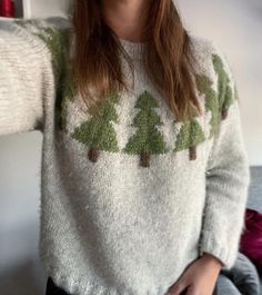 a woman wearing a sweater with trees on it