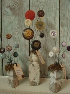 three small vases with buttons on them are sitting on a table next to a wooden wall