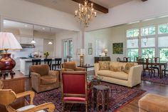 a living room filled with furniture and a chandelier hanging from the ceiling above it