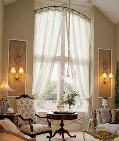 a living room filled with lots of furniture next to a large window covered in curtains