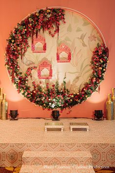 a table topped with flowers and vases next to a wall covered in floral decorations