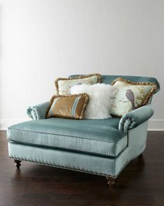 a blue couch with pillows on it in front of a white wall and wooden floor