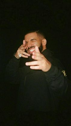 a man in black jacket holding his hand up to his face and smiling at the camera