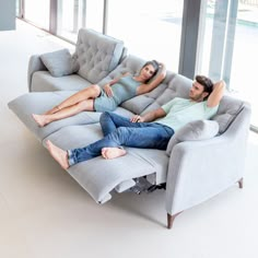 two people are lounging on a couch in the middle of an open floor plan