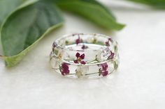 two rings with flowers on them sitting next to a leaf