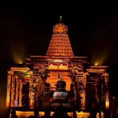 an illuminated temple at night with people standing around it