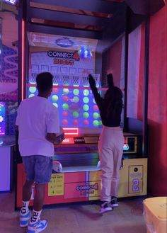 two young men play a game on the nintendo wii in front of an arcade machine