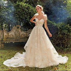 a woman in a wedding dress standing on the grass with her hand on her hip