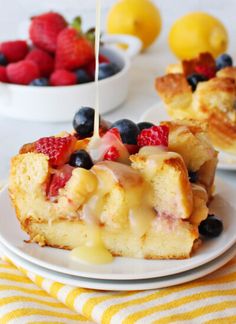 a piece of cake on a plate with strawberries and blueberries in the background