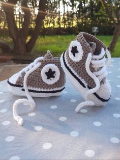 two crocheted baby shoes sitting on top of a blue tablecloth with white polka dots