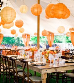 an outdoor tent with tables and chairs set up for a dinner or party under paper lanterns