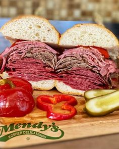 a cut in half sandwich sitting on top of a cutting board next to sliced peppers