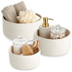 two white baskets with soap, toothbrushes and other bathroom items in them on a white background