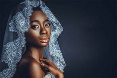 a woman wearing a veil and posing for a photo in front of a dark background